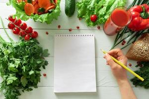 notitieboekje voor het bijhouden van een dagboek van gewichtsverlies op de achtergrond van groenten. het opstellen van een individueel dieet. foto