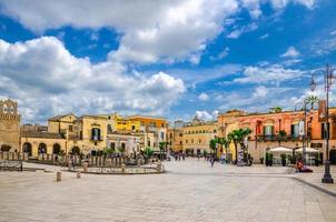 mensen toeristen lopen langs piazza vittorio veneto plein met stenen gebouwen in het historische centrum van de oude stad van Matera foto