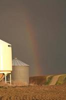 regenboog die neerkomt achter graanschuren in Saskatchewan