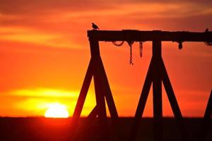 zonsondergang achter een old school schommel in het schilderachtige Saskatchewan foto