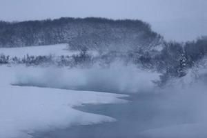 mist die in de winter opstijgt uit open water foto