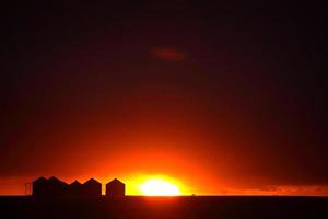 ondergaande zon achter metalen graanschuren in Saskatchewan