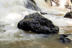 donkere rots te midden van een stroom van water foto