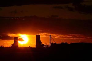 zonsondergang achter twee graanelevators in Saskatchewan foto