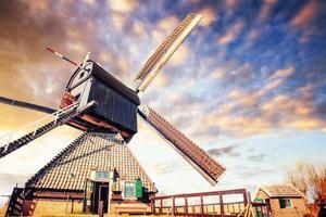 kleurrijke lentedag met traditionele Nederlandse windmolens kanaal in rotterdam. houten pier in de buurt van de oever van het meer. Holland. Nederland foto