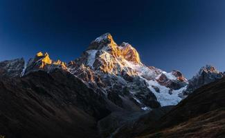 herfstlandschap en sneeuwbergen in prachtige cumuluswolken. belangrijkste kaukasische bergkam. type mount ushba mheyer, georgië foto