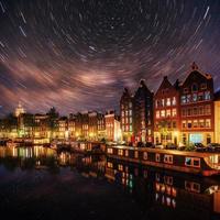 prachtige nacht in amsterdam. nachtverlichting van gebouwen en boten aan het water in het kanaal. foto