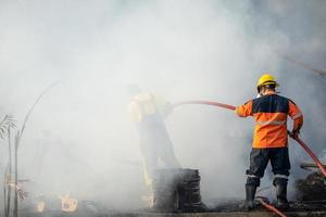 brandweerman spuit water uit grote waterslang om brand te voorkomen foto