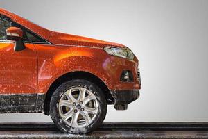 oranje auto met witte zeep op het lichaam in autoverzorgingswinkel foto