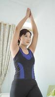 Aziatische vrouw die thuis yoga beoefent en handwarming doet foto