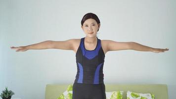 Aziatische vrouw die thuis yoga beoefent en handgebaar opwarmt foto