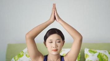 aziatische vrouw die thuis yoga beoefent en hand omhoog beweegt foto