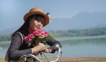 jonge aziatische vrouw geniet van fietsen terwijl ze stopt met bloemen in het park foto