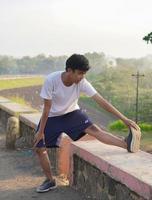jonge aziatische man die zich uitstrekt voordat hij 's ochtends jogt? foto