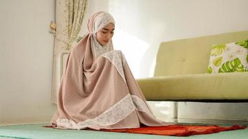 moslimvrouw die bidt en bidt met een mukenah foto