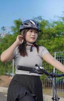 jonge aziatische vrouw geniet van fietsen wanneer gestopt in de zomerochtend foto