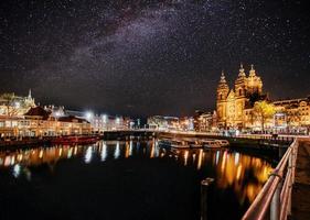 prachtige nacht in amsterdam. nachtverlichting van gebouwen en boten aan het water in het kanaal. foto