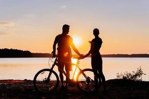 koppel op de fiets bij zonsondergang aan het meer foto