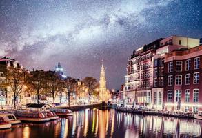 prachtige nacht in amsterdam. nachtverlichting van gebouwen en boten aan het water in het kanaal. foto