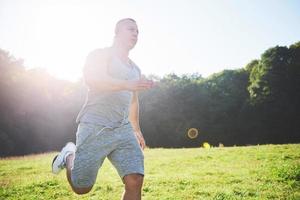 fitness man atleet joggen in de natuur tijdens zonsondergang. persoon die aan het trainen is, een actieve levensstijl leidt die cardio traint in de zomer in sportkleding en schoenen. foto