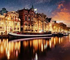 prachtige nacht in amsterdam. nachtverlichting van gebouwen en boten aan het water in het kanaal. foto