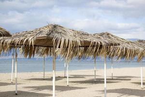exotisch strand op het strand met parasol. een eenzame lege parasol gemaakt van riet. mooie droge takken van palmbomen op het dak tegen de achtergrond van het strand. foto