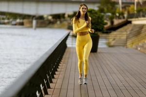 jonge vrouw die op de pier aan de rivier loopt