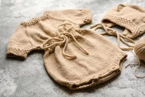 baby gebreide beige kleding op een witte betonnen ondergrond foto