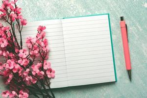 bovenaanzicht van blanco dagboek open met kopieerruimte, roze pen en amandelbloesems foto