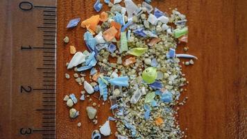 macro-opname van authentieke echte microplastic deeltjes verzameld van het strand met een liniaal om hun grootte te laten zien. watervervuiling en opwarming van de aarde concept. foto