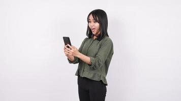 Aziatische vrouw kijkt naar de mobiele telefoon met een geschokte uitdrukking geïsoleerd op een witte achtergrond foto