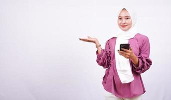 mooie vrouwen hijab wijzend gebied en houd telefoon geïsoleerd witte achtergrond foto