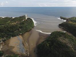 luchtfoto van baron beach in gunung kidul, indonesië met vuurtoren en traditionele boot. foto