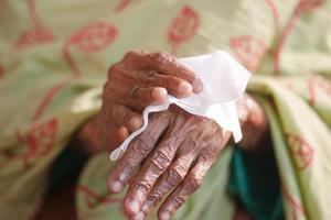 oudere vrouwen die zijn handen desinfecteren met een nat doekje. foto