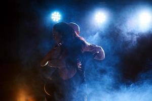 bekwame dansers presteren in de donkere kamer onder het concert licht en rook. sensueel stel dat een artistieke en emotionele hedendaagse dans uitvoert foto