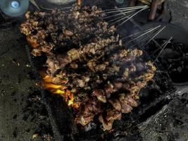 geit saté op rood vuur grillen door mensen. traditionele Indonesische gerechten gemaakt van schapenvlees. foto