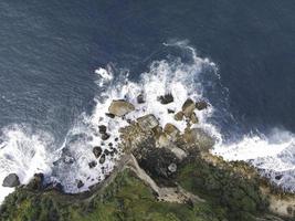 top-down luchtfoto van gigantische oceaangolven die beuken en schuimen in koraalstrand foto