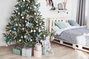 mooie ruim ingerichte kamer met kerstboom met cadeautjes eronder foto