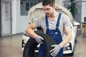 monteur die een bandband vasthoudt bij de reparatiegarage. vervanging van winter- en zomerbanden foto