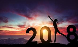 silhouet jonge vrouw die naar 2018 nieuw jaar springt foto