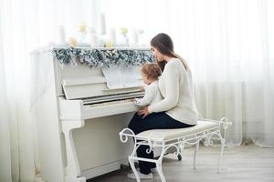 kijk van achteren naar moeder en dochter die witte piano spelen foto