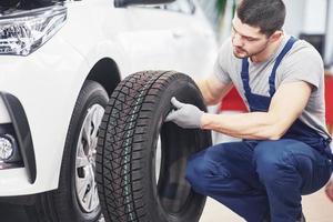 monteur die een bandband vasthoudt bij de reparatiegarage. vervanging van winter- en zomerbanden foto