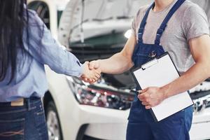 man automonteur en vrouw klant maken een overeenkomst over de reparatie van de auto foto