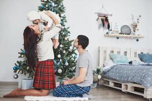 gelukkige familie met kerstmis in de ochtend die geschenken samen opent in de buurt van de dennenboom. het concept van gezinsgeluk en welzijn foto