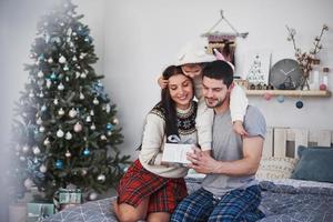 gelukkige familie met kerstmis in de ochtend die geschenken samen opent in de buurt van de dennenboom. het concept van gezinsgeluk en welzijn foto