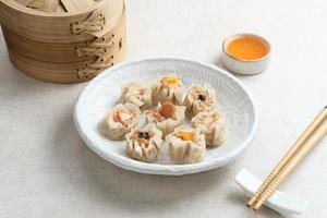 mini dim sum chinese dumplings geserveerd op een witte plaat, met saus en eetstokje. detailopname. foto