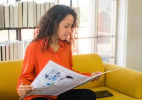 Latijns-Amerikaanse vrouw leest de krant op de bank foto