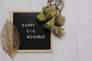 bovenaanzicht van letterbord zegt happy eid mubarak en traditioneel eten tijdens lebaran-viering genaamd ketupat met kopieerruimte foto