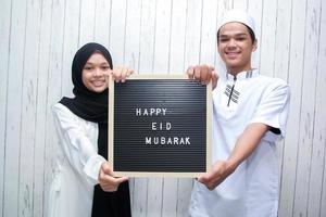 Aziatisch moslimpaar met een briefbord zegt gelukkige eid mubarak foto