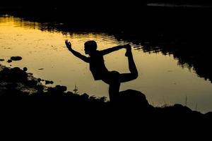 silhouetten van een vrouw die yoga doet bij zonsondergang foto